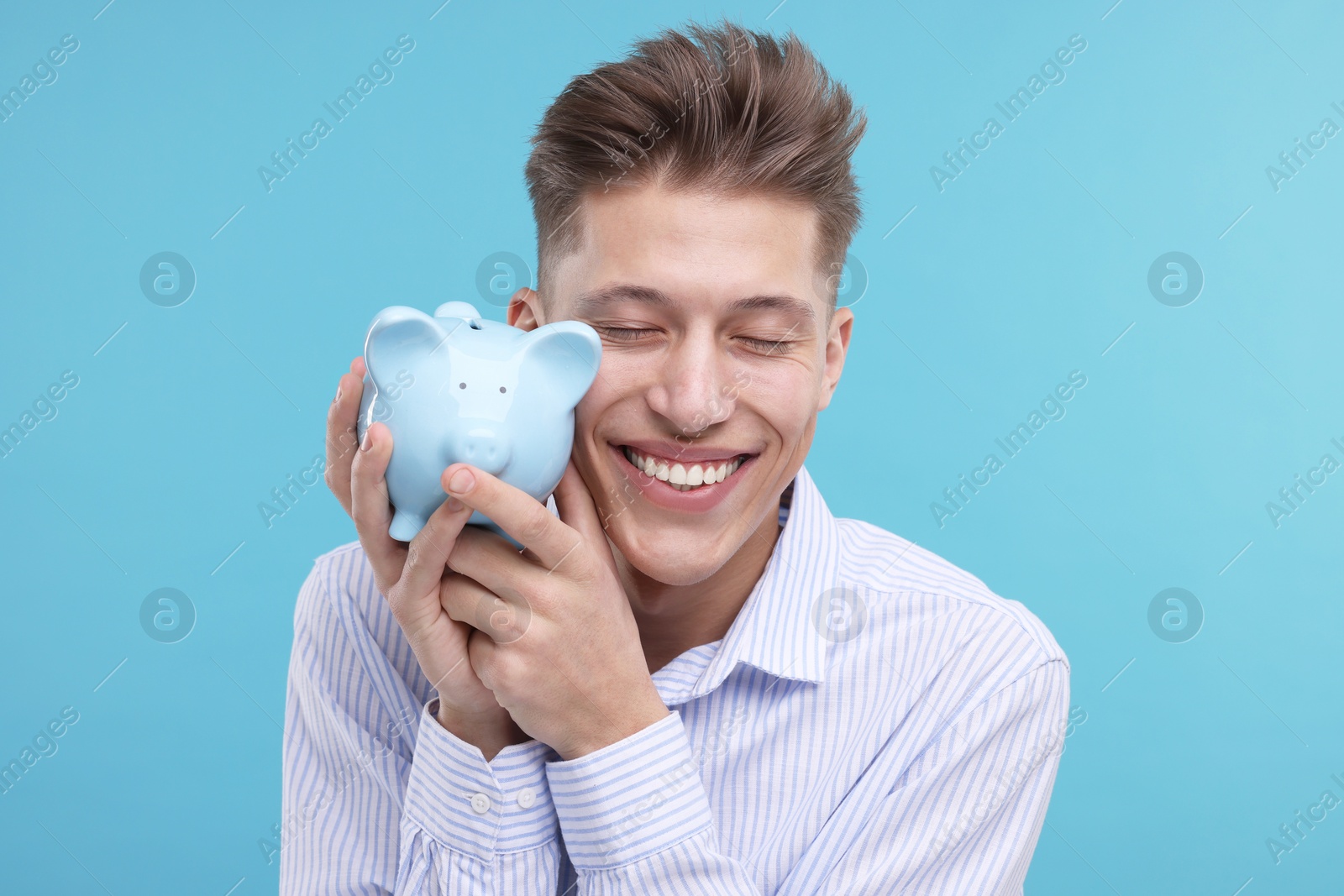 Photo of Happy man with piggy bank on light blue background