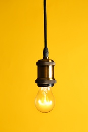 Photo of Hanging modern lamp bulb against yellow background