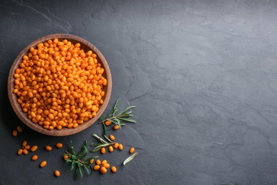 Fresh ripe sea buckthorn on black table, flat lay. Space for text