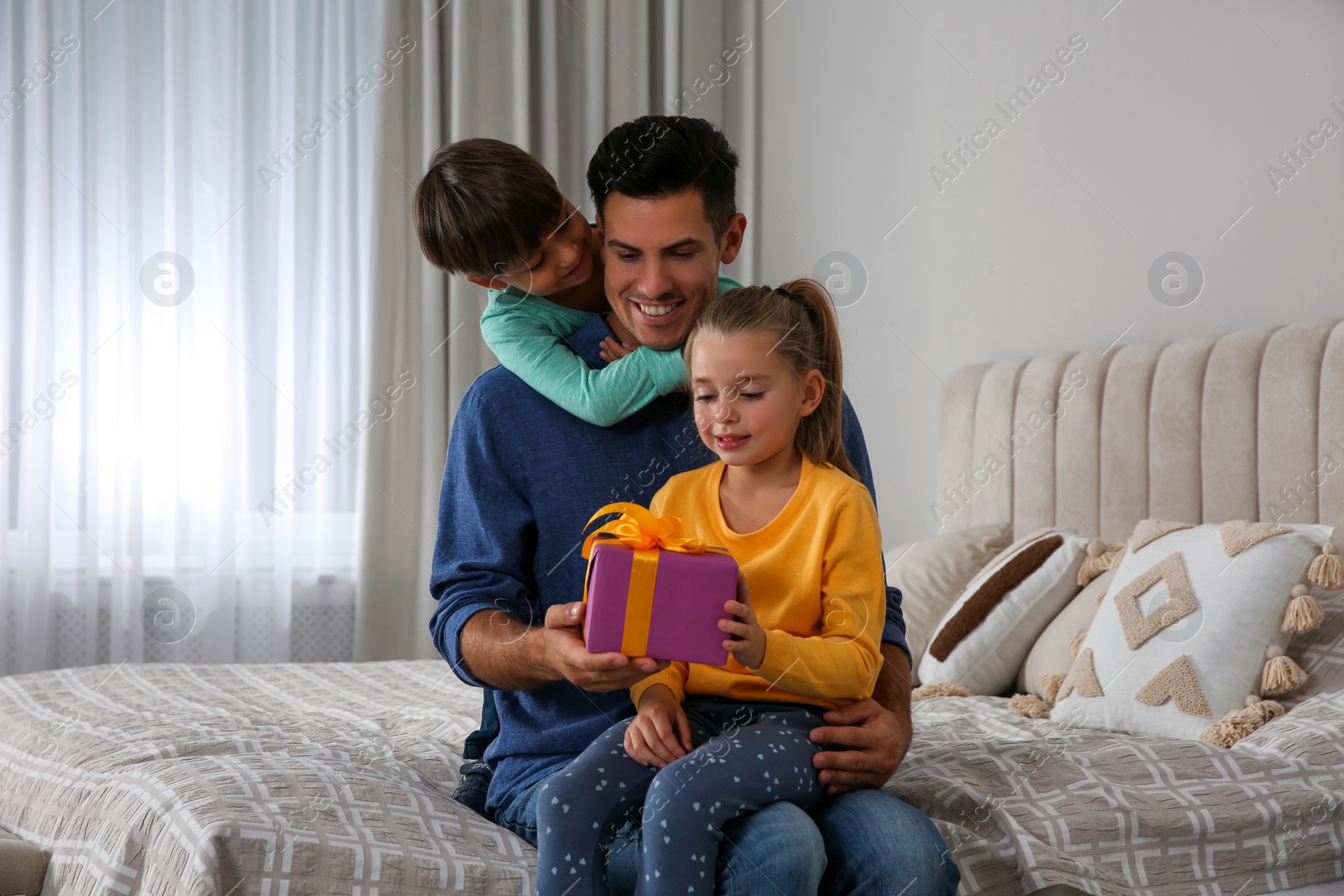 Photo of Man receiving gift for Father's Day from his children at home