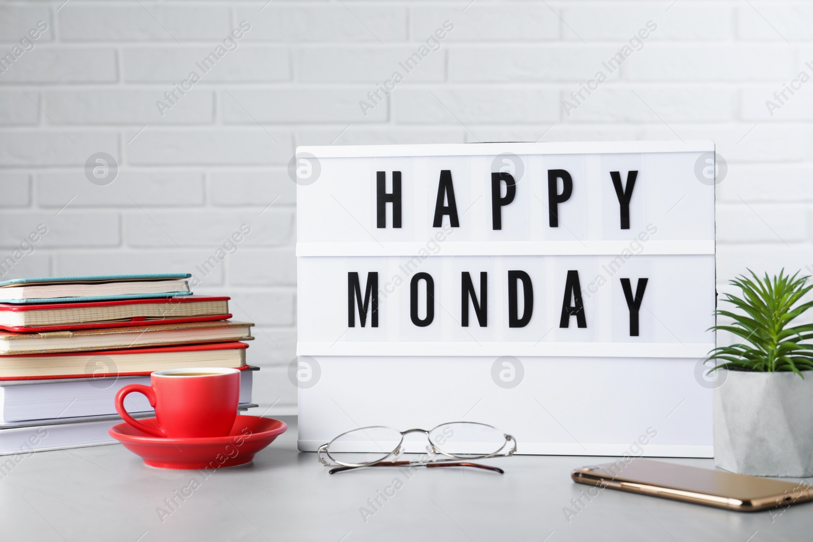 Photo of Light box with message Happy Monday, office stationery and cup of coffee on desk