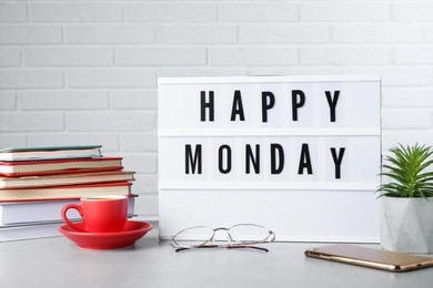 Photo of Light box with message Happy Monday, office stationery and cup of coffee on desk