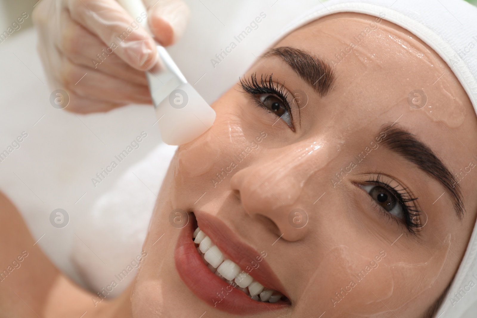 Photo of Young woman during face peeling procedure in salon, closeup