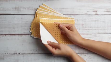 Photo of Woman opening pepper plaster at white wooden table, top view