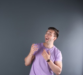 Handsome emotional young man on color background