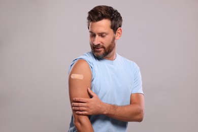 Photo of Man with sticking plaster on arm after vaccination against light grey background