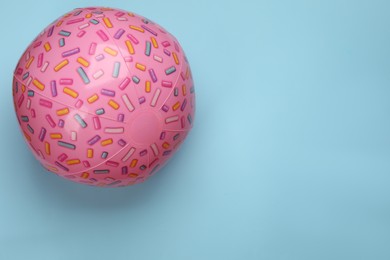 Photo of Pink beach ball on light blue background, top view. Space for text