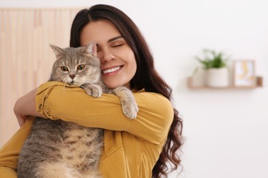 Photo of Young woman with adorable cat at home, space for text