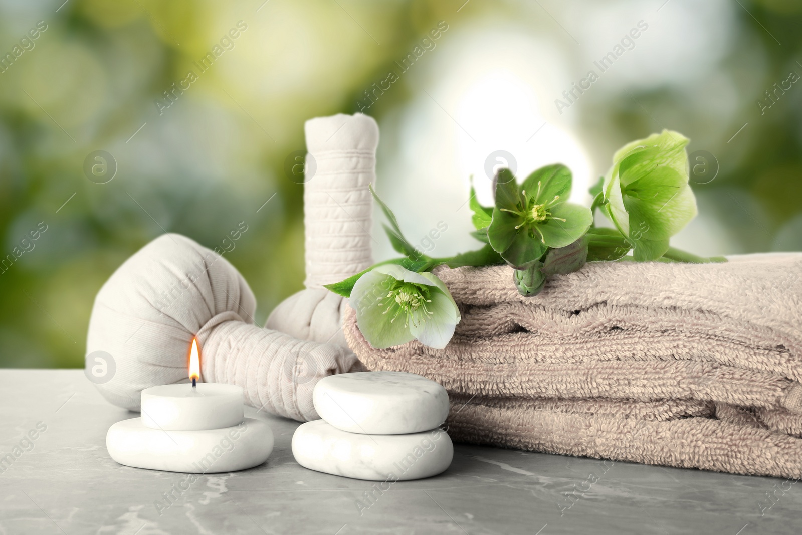 Image of Composition with flowers and spa supplies on marble table against blurred green background