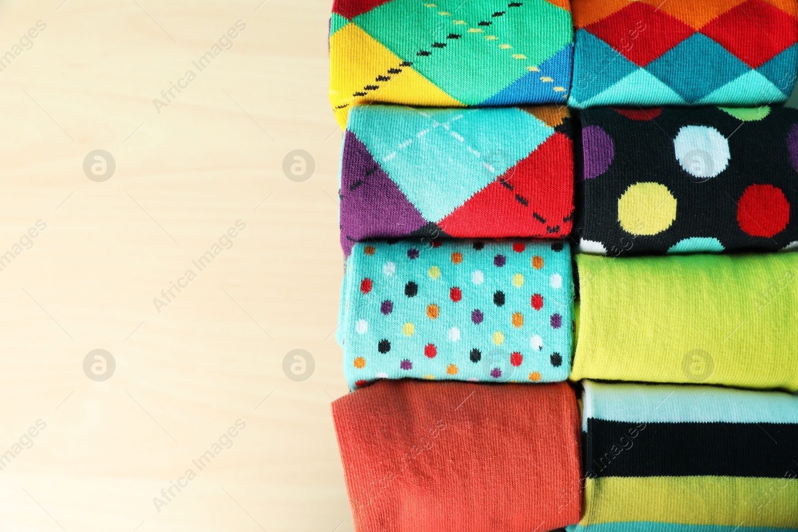 Photo of Rolled colorful socks on light background, top view