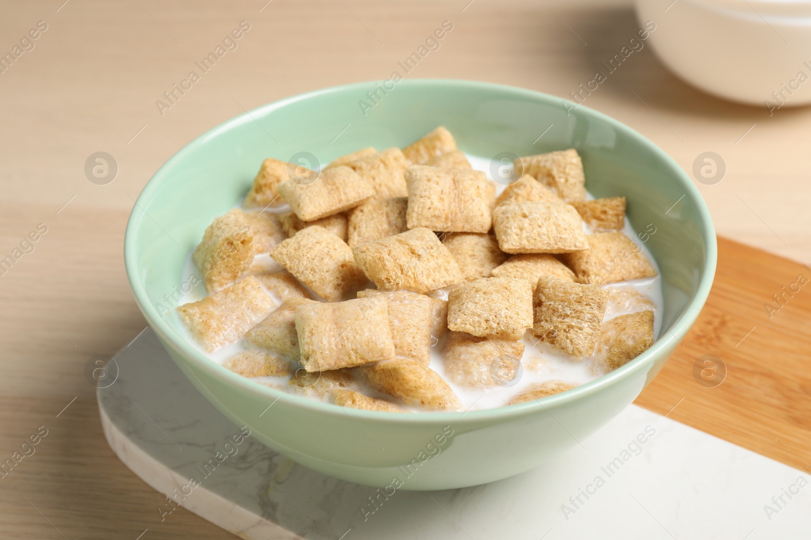 Photo of Bowl with tasty corn pads and milk on wooden table, closeup