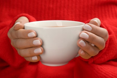 Photo of Woman with white polish on nails holding cup of hot drink, closeup