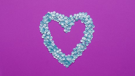 Photo of Heart made of silver sequins on purple background, top view