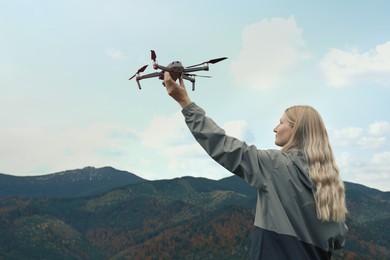 Photo of Young woman with modern drone in mountains