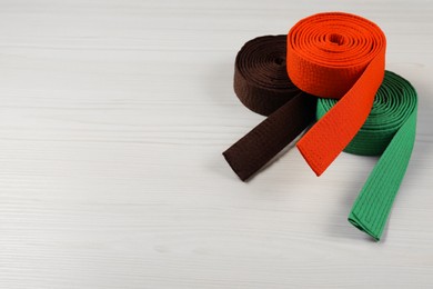 Photo of Colorful karate belts on wooden background, space for text