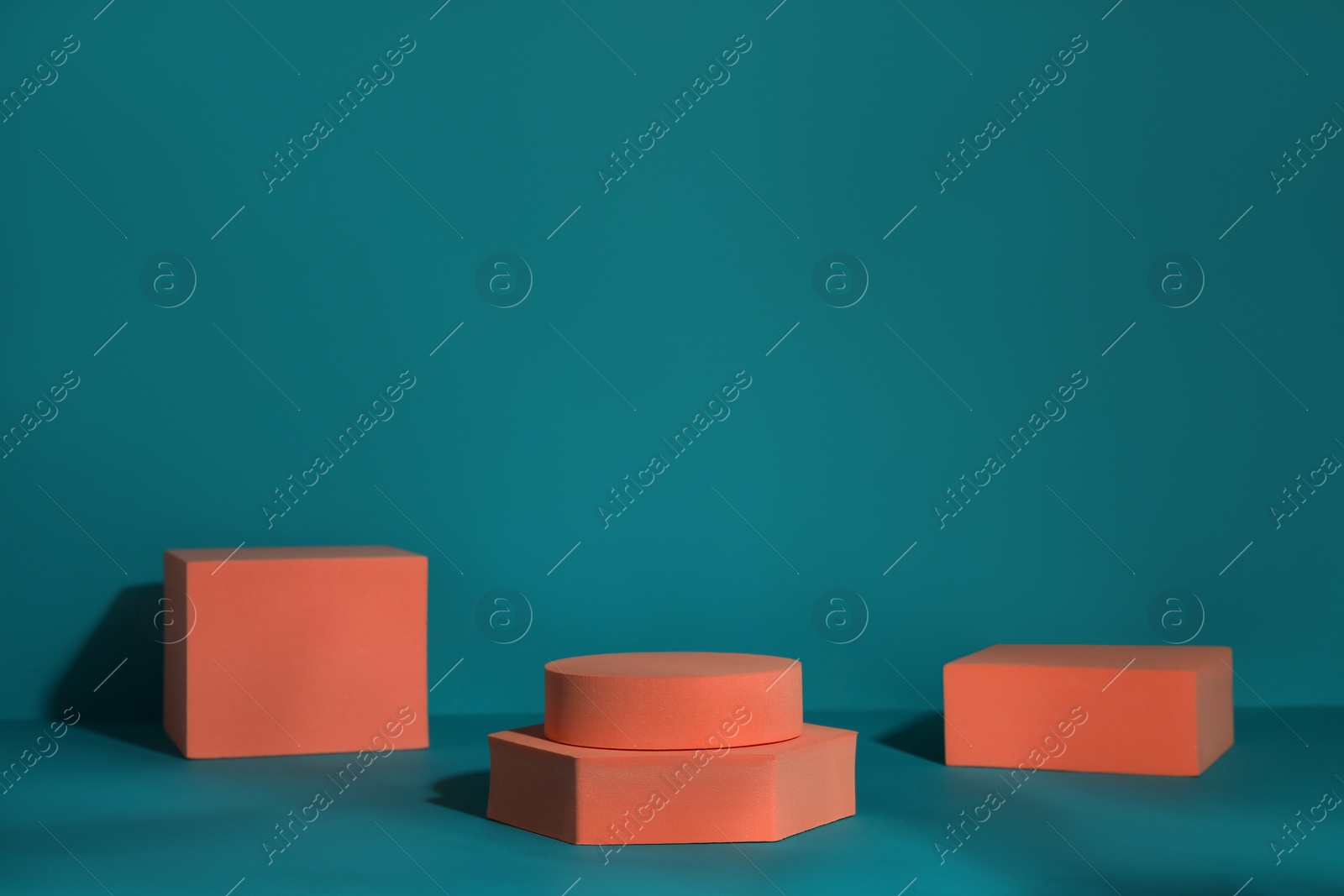 Photo of Many orange geometric figures on teal background, space for text. Stylish presentation for product