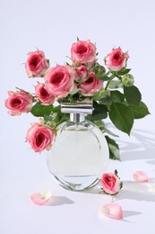 Photo of Bottle of luxury perfume and beautiful roses on white background. Floral fragrance