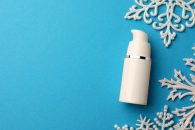 Hand cream and snowflakes on light blue background, flat lay with space for text. Winter skin care