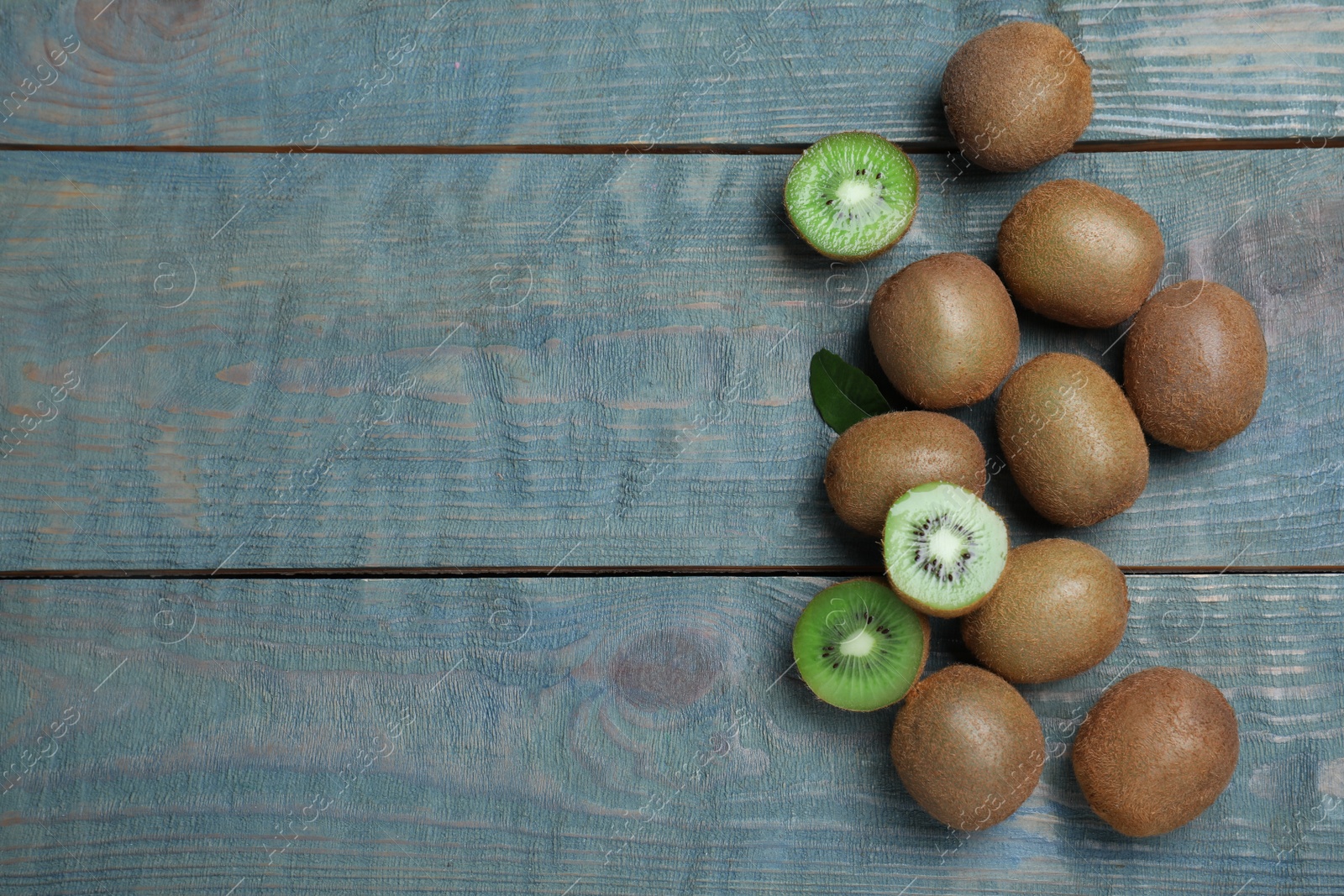 Photo of Fresh ripe kiwis on light blue wooden table, flat lay. Space for text
