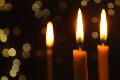 Image of Burning candles on dark background with blurred lights, closeup. Bokeh effect