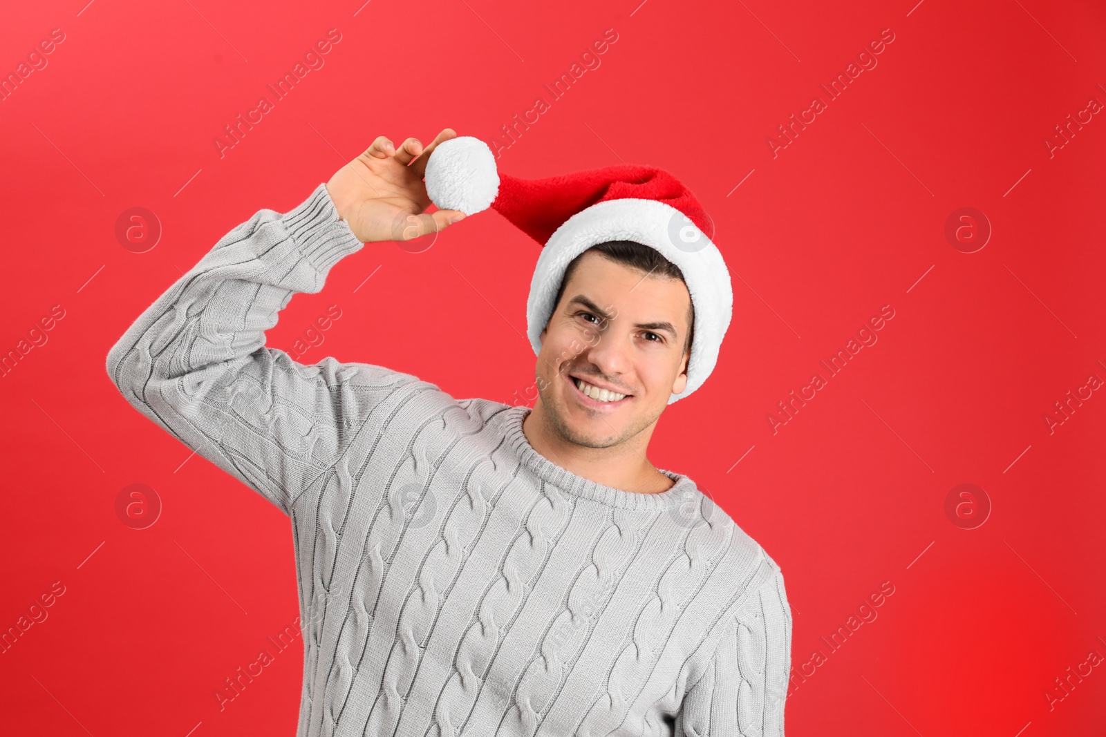 Photo of Happy man wearing Santa hat on red background