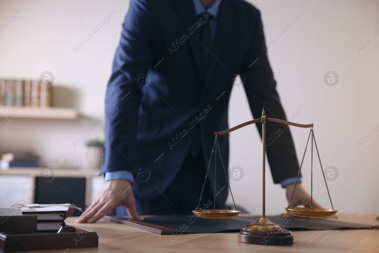 Photo of Male lawyer at table in office, focus on scales of justice