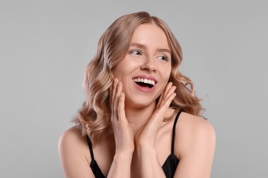 Portrait of beautiful woman with blonde hair on light grey background