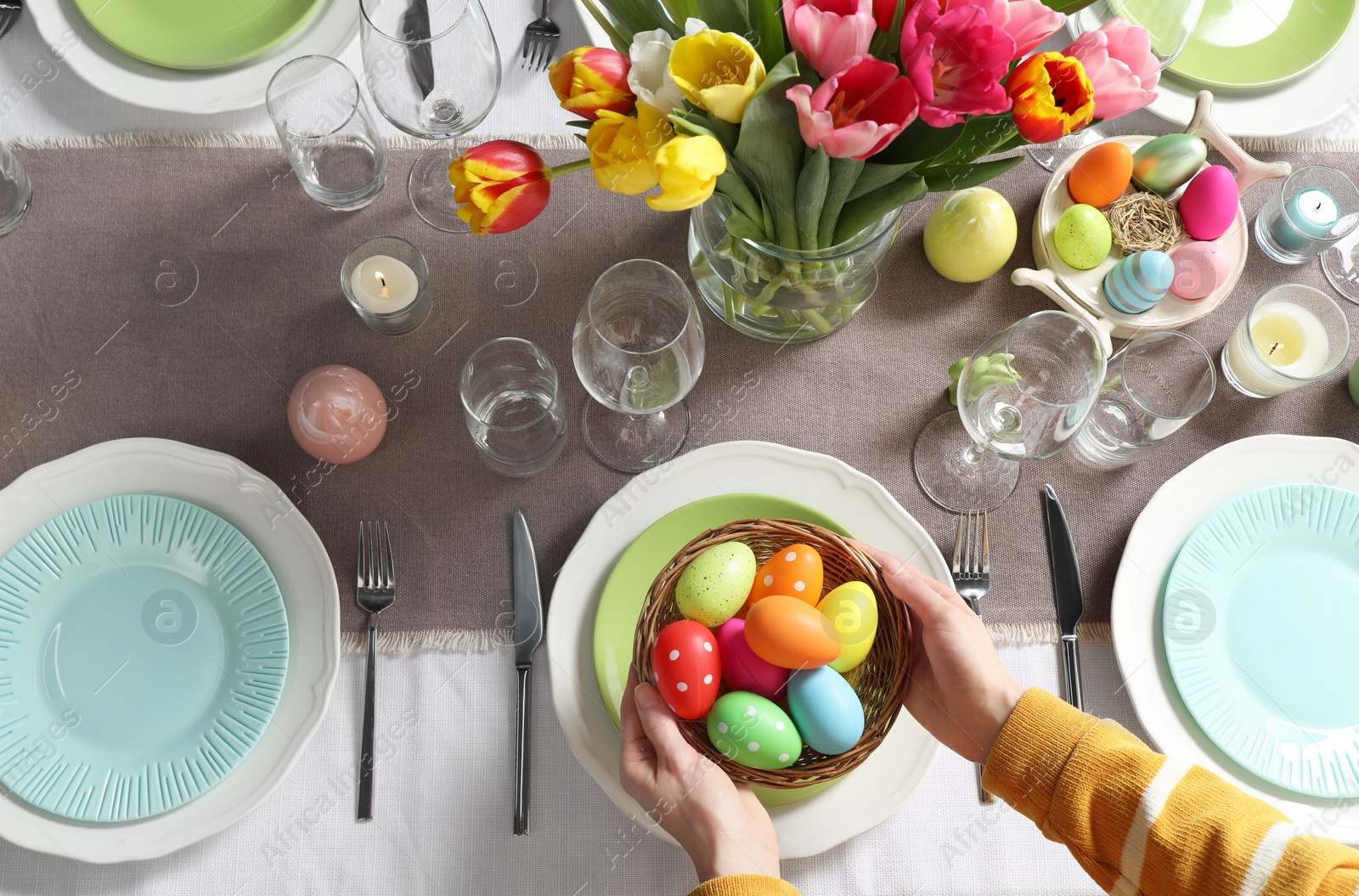 Photo of Woman setting table for festive Easter dinner at home, top view