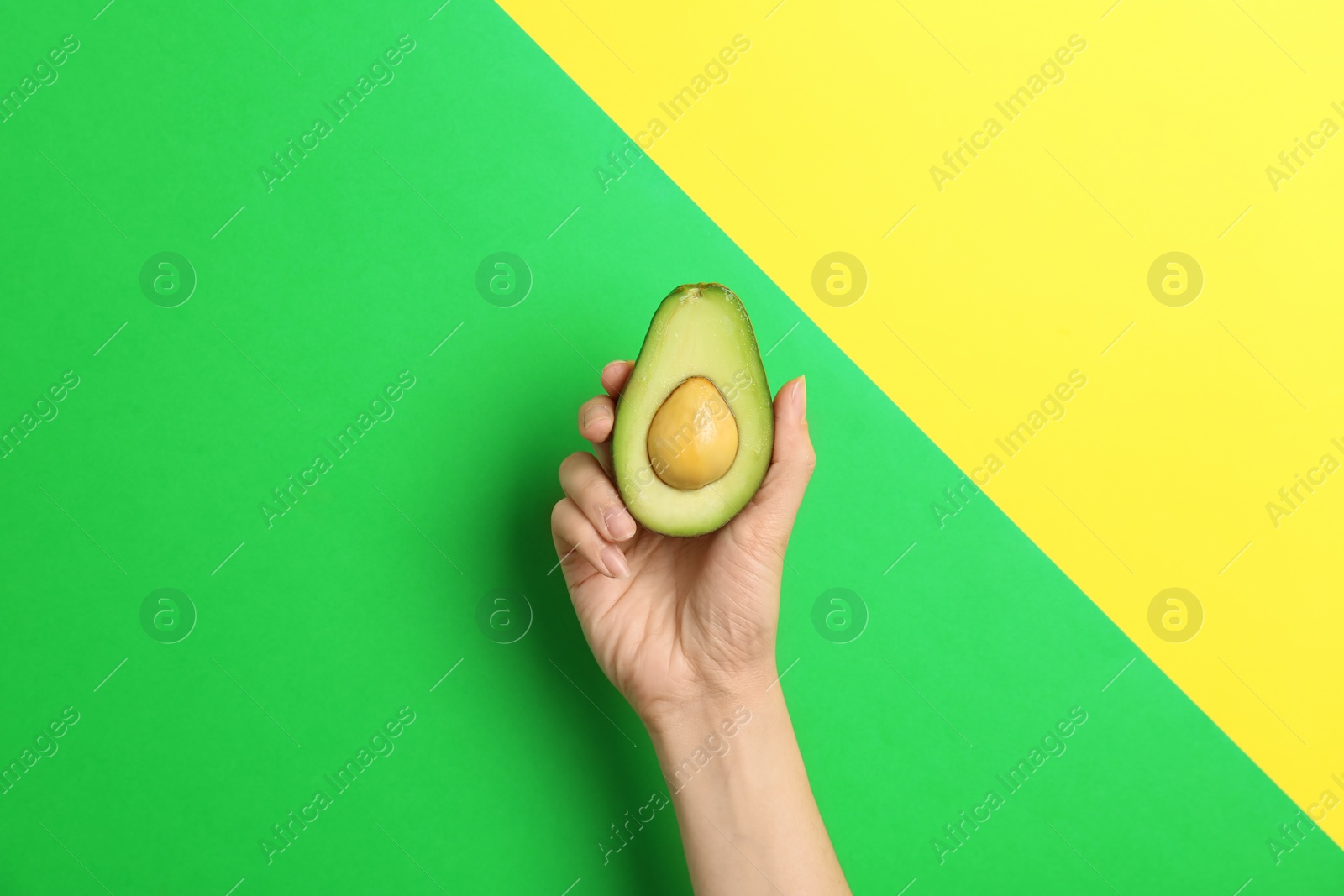 Photo of Woman holding ripe cut avocado on color background