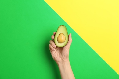 Photo of Woman holding ripe cut avocado on color background