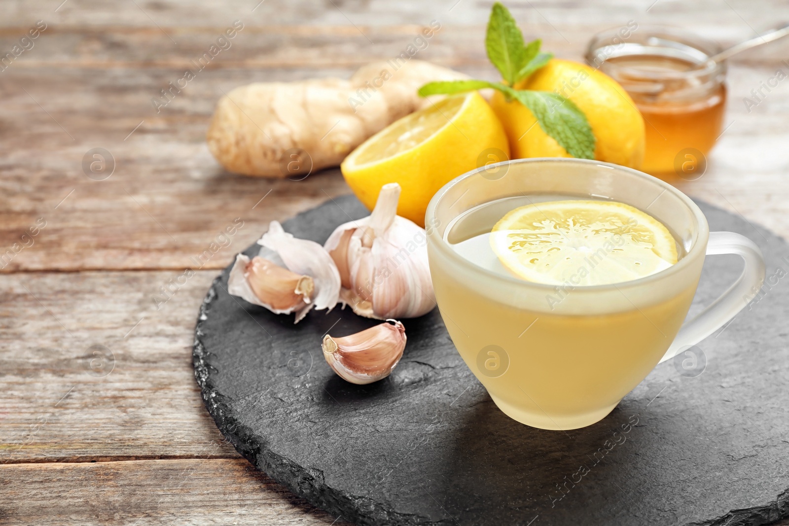 Photo of Cup with hot tea and lemon for cold on slate plate