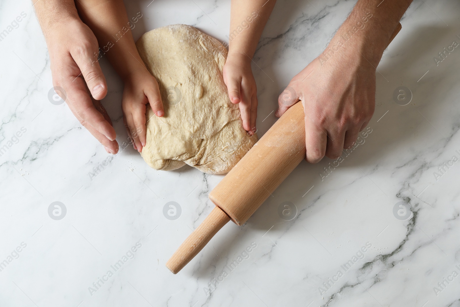 Photo of Father and child making dough at white table, top view