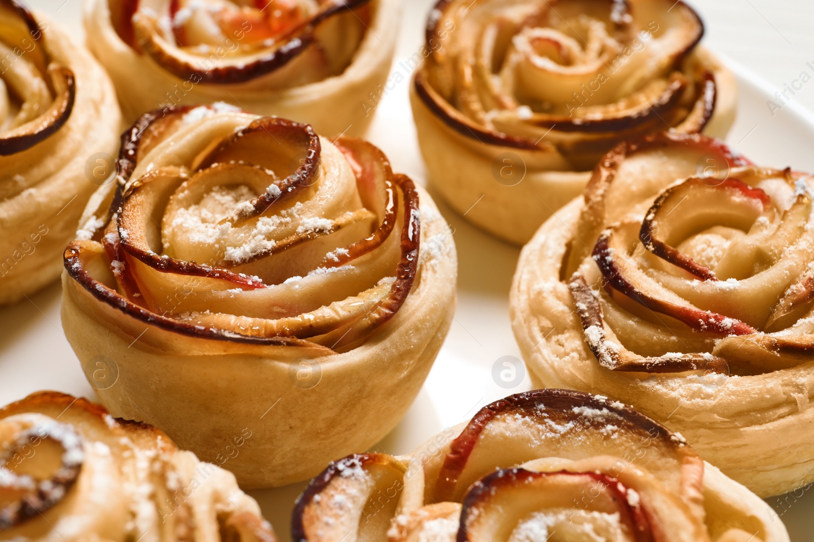 Photo of Freshly baked apple roses on plate, closeup. Beautiful dessert