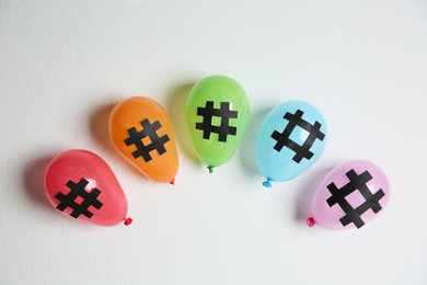 Photo of Bright balloons with hashtag symbols on white background