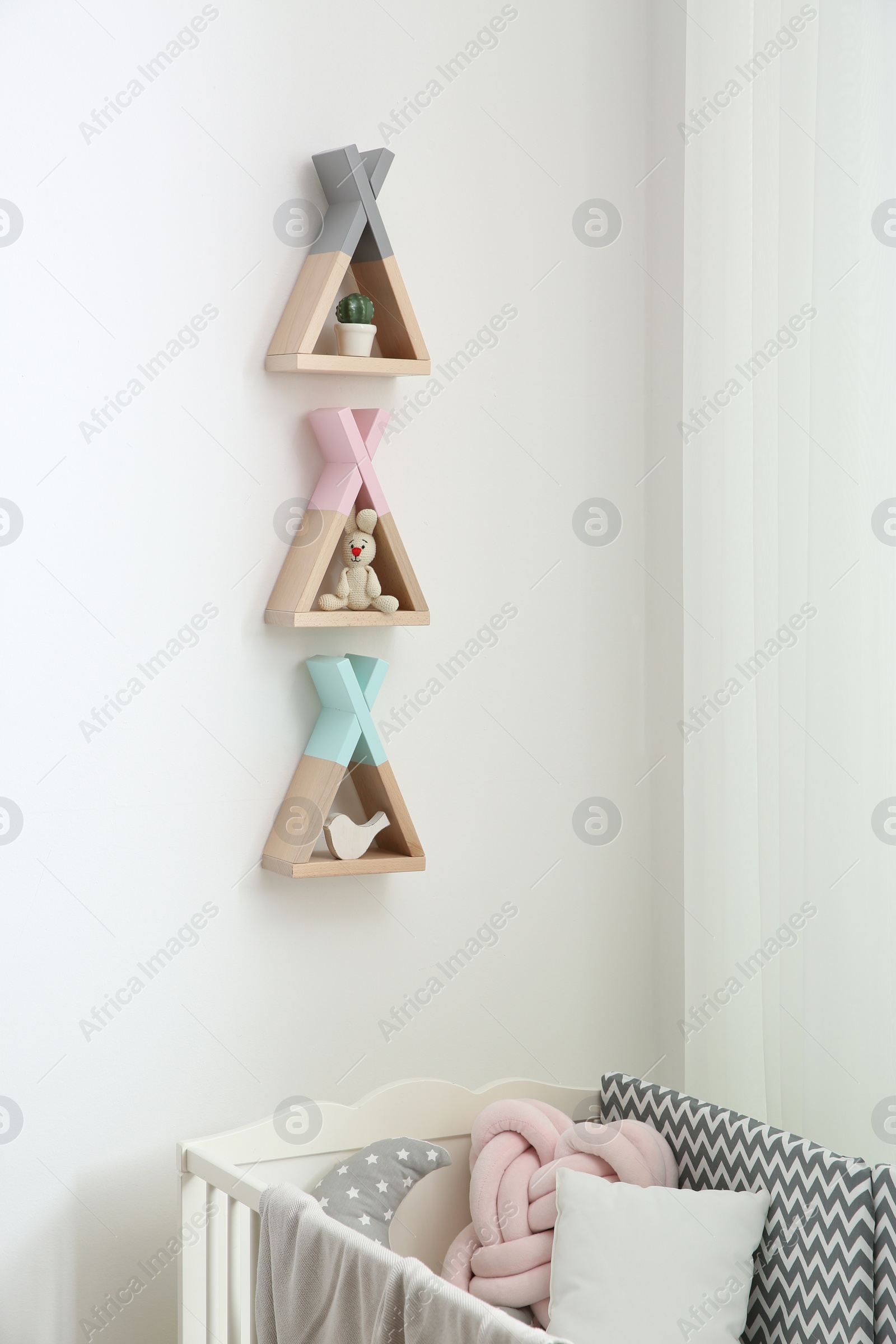 Photo of Wigwam shaped shelves over crib in baby room. Interior design