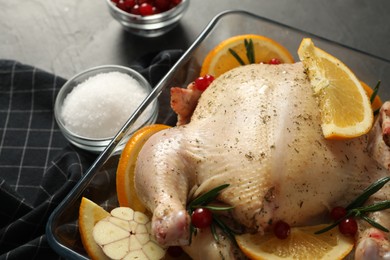 Photo of Chicken with orange slices, rosemary and berries on grey table