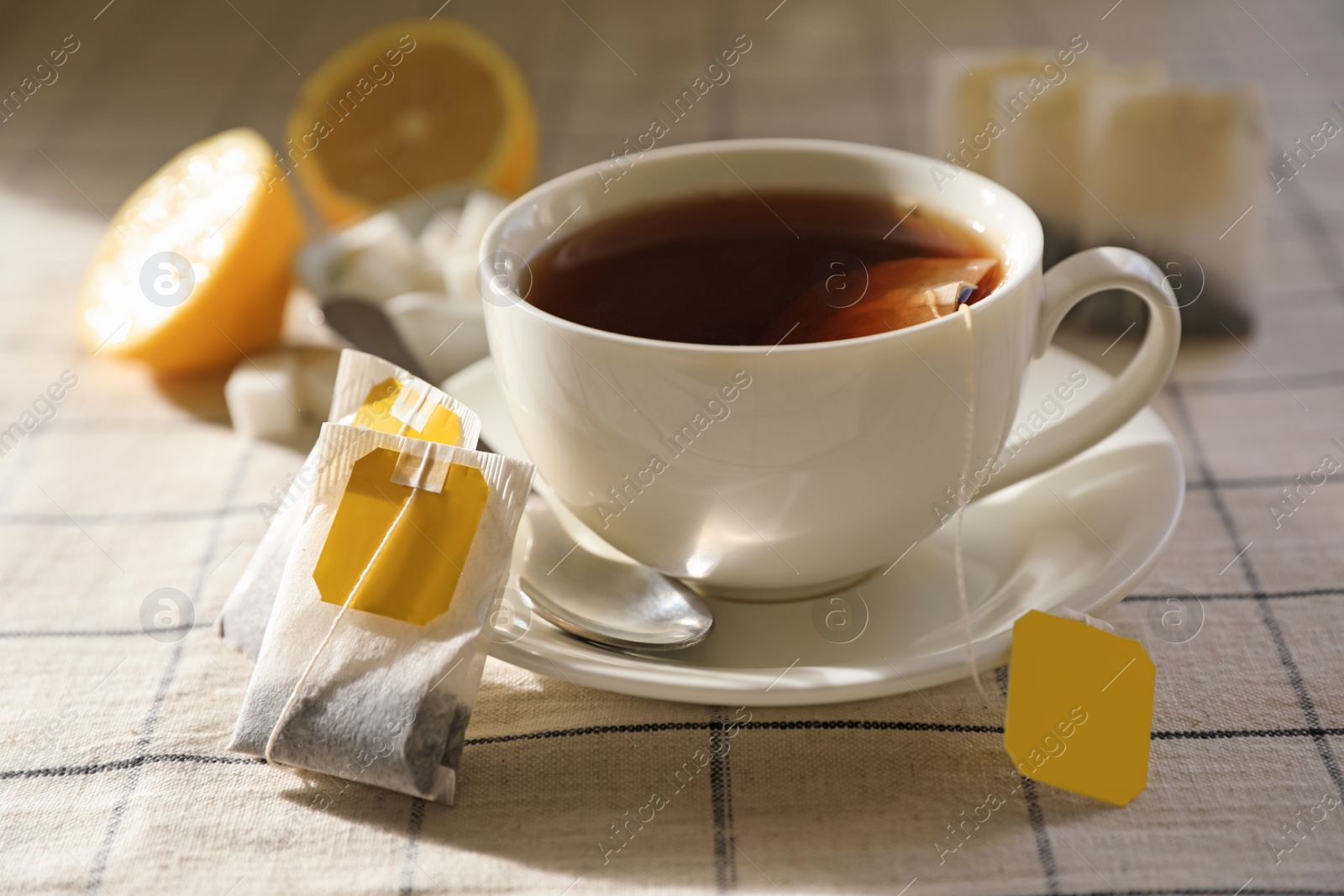 Photo of Tea bags near cup of hot drink on table, closeup