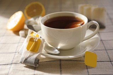 Tea bags near cup of hot drink on table, closeup