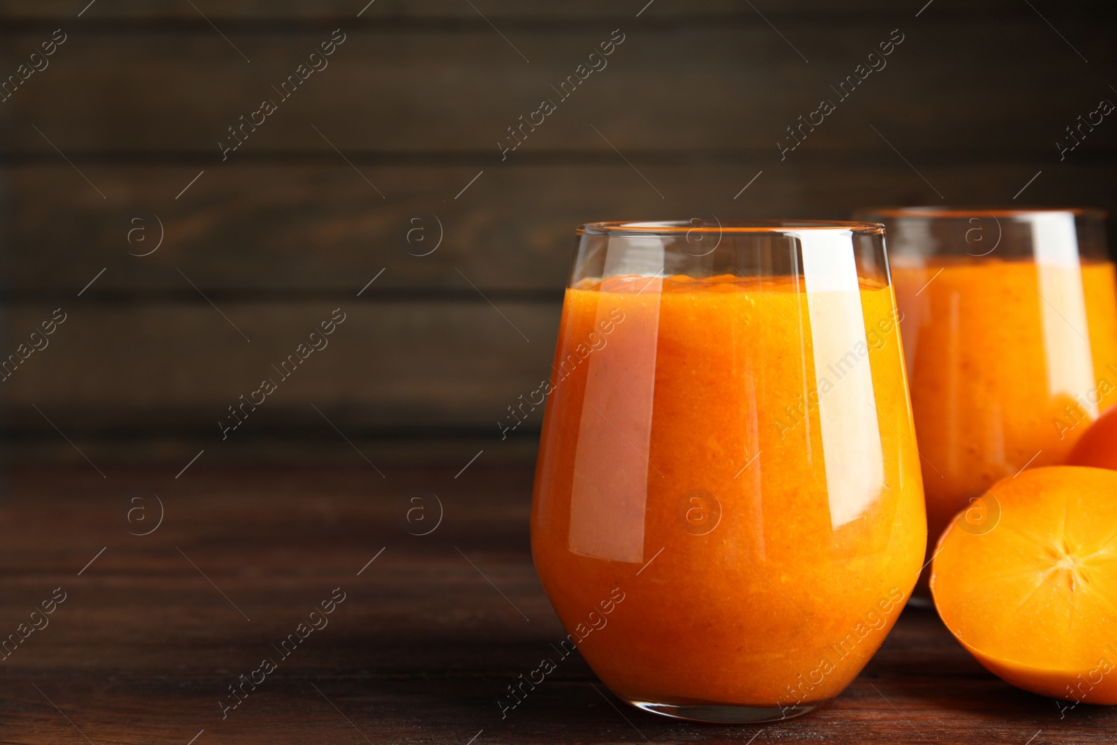 Photo of Tasty persimmon smoothie and fresh fruit on wooden table, closeup. Space for text