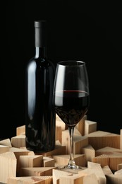 Photo of Stylish presentation of red wine in bottle and wineglass on black background
