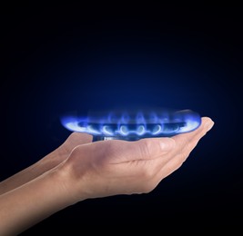 Image of Closeup view of woman holding gas burner with blue flame on black background