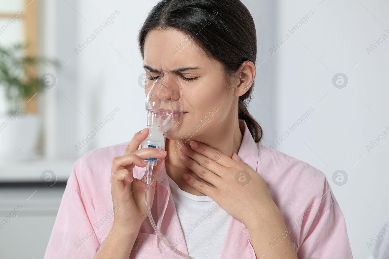 Photo of Sick young woman using nebulizer at home