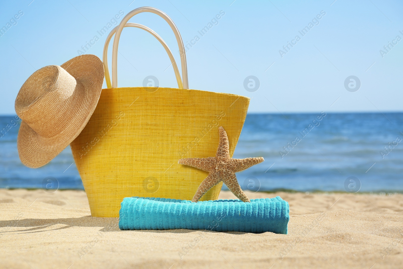 Photo of Stylish beach accessories on sand near sea. Space for text