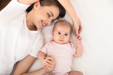 Portrait of mother with her cute baby lying on bed, top view