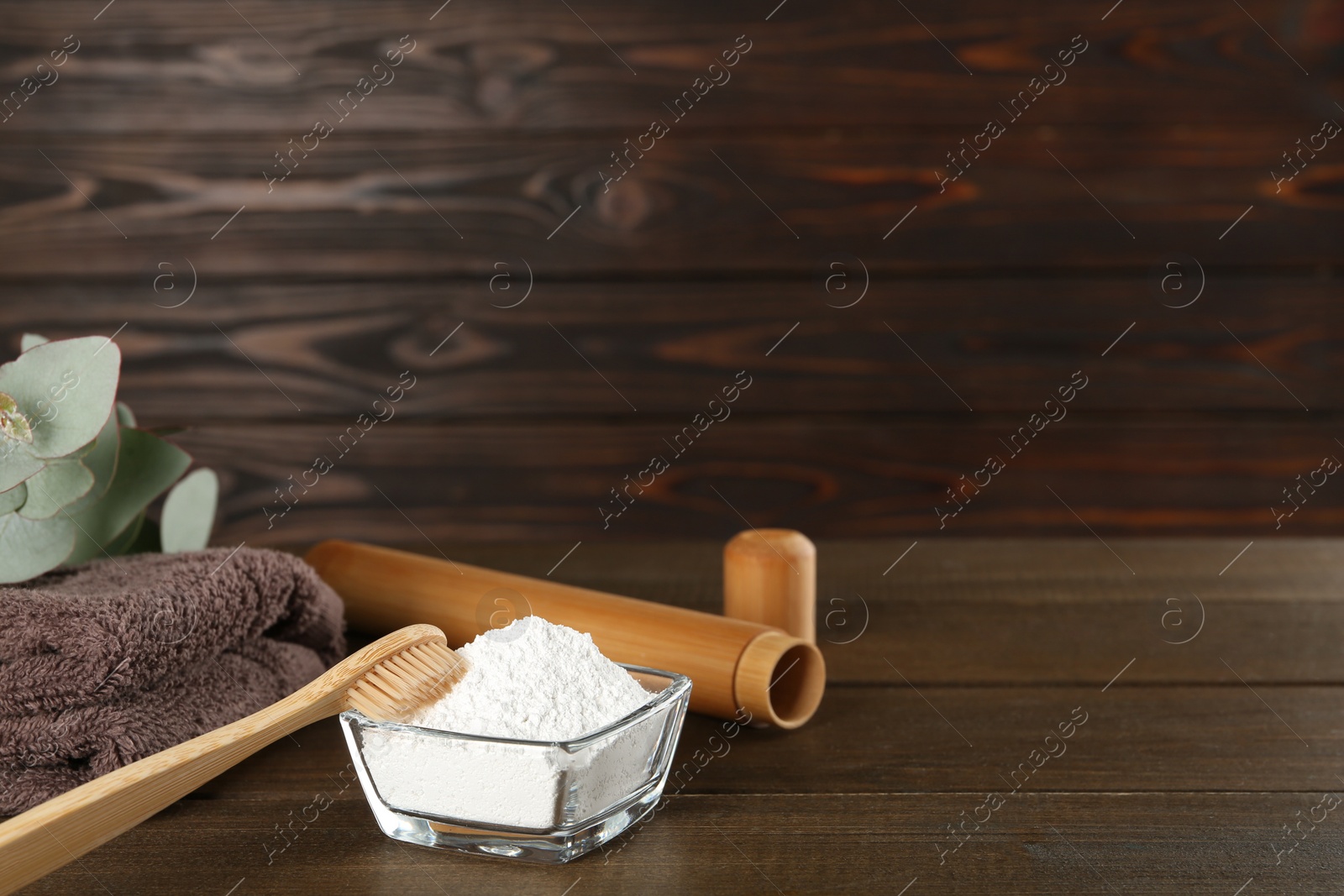 Photo of Tooth powder, towel, brush and eucalyptus on wooden table, space for text