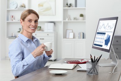 Photo of Professional accountant drinking coffee at workplace in office