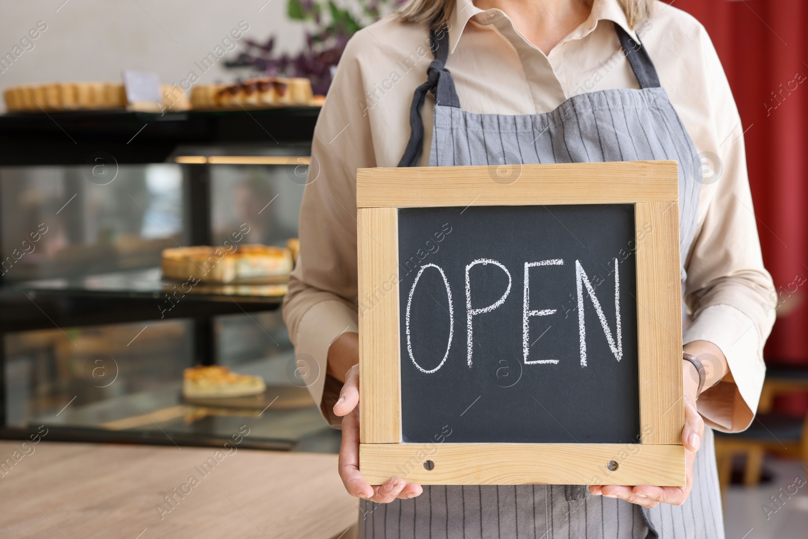 Photo of Business owner holding open sign in her cafe, closeup. Space for text