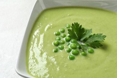 Photo of Fresh vegetable detox soup made of green peas in dish, closeup