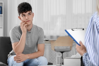 Photo of Psychologist working with teenage boy in office. Teenager problems