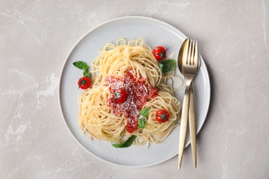 Photo of Tasty pasta with tomatoes, cheese and basil on light grey marble table, top view
